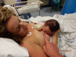 Mother nursing newborn in a reclined position in a hospital bed