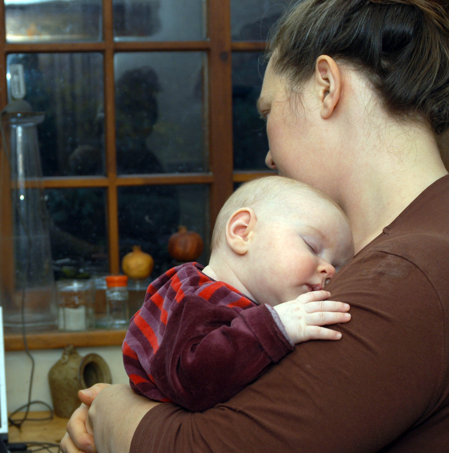 mother in kitchen holding sleeping baby