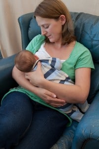 Mother supporting breastfeeding baby with both arms