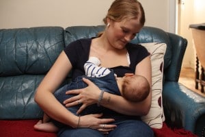 Mum on sofa concentrating on holding baby's body firmly into hers