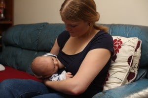 Mother concentrating hard on feeding baby in rugby hold