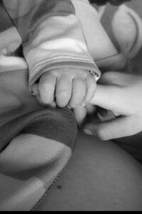 Black and White photo, close up of a baby holding their parents finger.